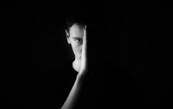 Zdjęcie twarzy mężczyzny z dłonią na czarnym tle